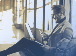 Business traveller working on his laptop and mobile devices denoting expense reporting on mobile devices